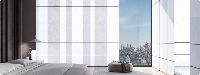 Minimalist bedroom with white translucent panel shades and a view of a snowy forest